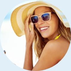 Uśmiechnięta kobieta w okularach przeciwsłonecznych i kapeluszu